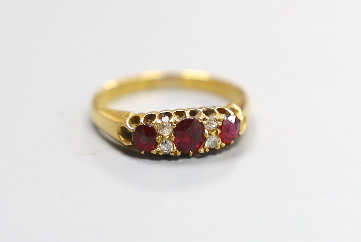 A late Victorian 18ct gold, three stone ruby and four stone diamond set half hoop ring, size M, gross 2.9 grams.